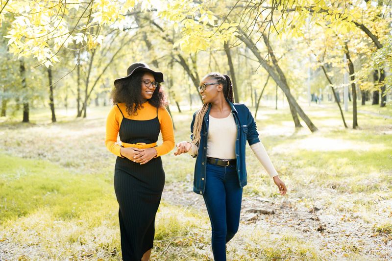 happy african women friends walking outdoors in the park