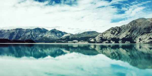 A serene landscape featuring mountains, a lake, and a clear blue sky, ideal for relaxation and nature appreciation.