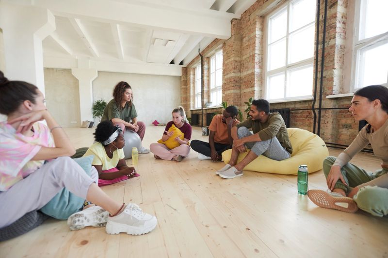 Group of young people sitting on the floor discussing new dance together in dance studio