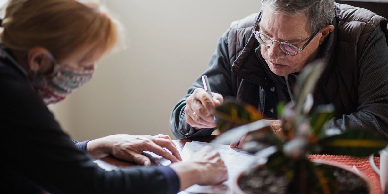 Two elderly people signing documents at a table indoors.