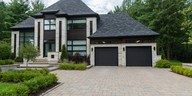 Modern custom-built home with a stone driveway, two-car garage, and elegant front-yard landscaping.