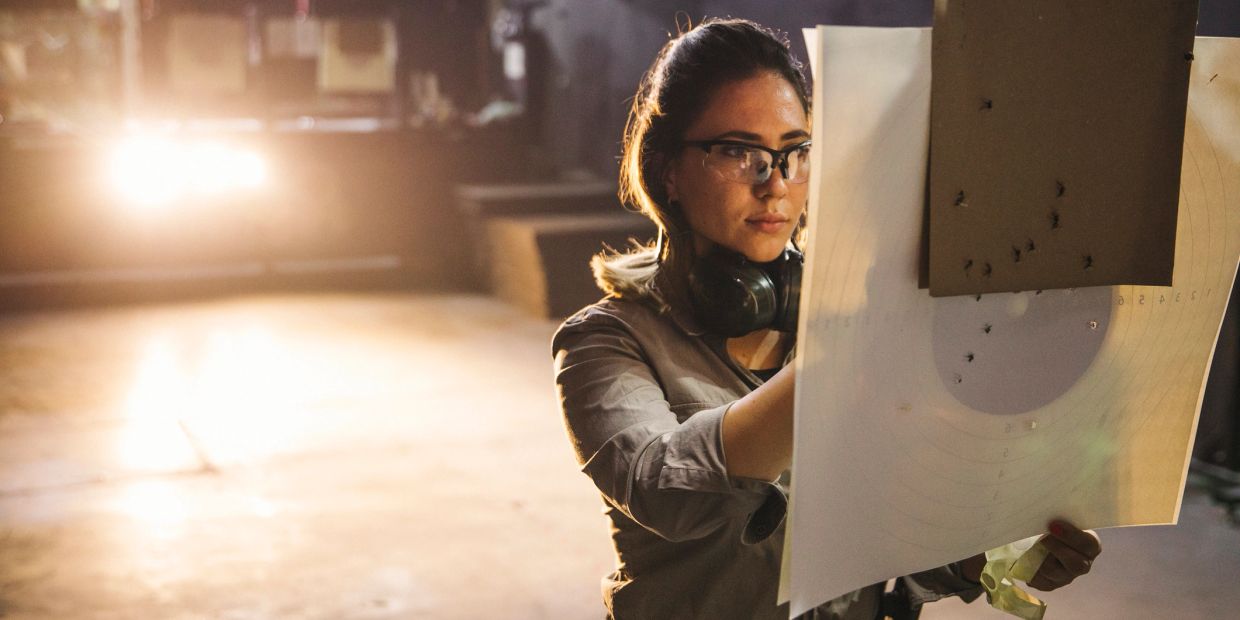 Woman analyzing a shooting target at a gun range.