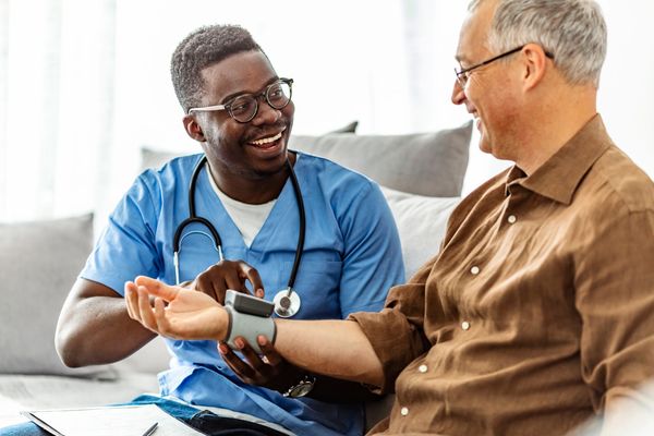 Nurse measuring elderly man's blood pressure with a smile.