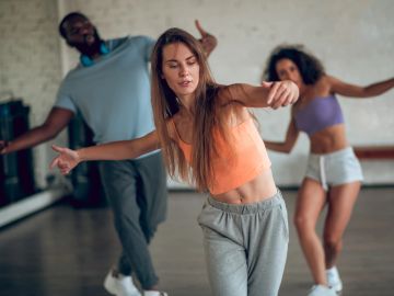 Three people dance energetically together indoors.