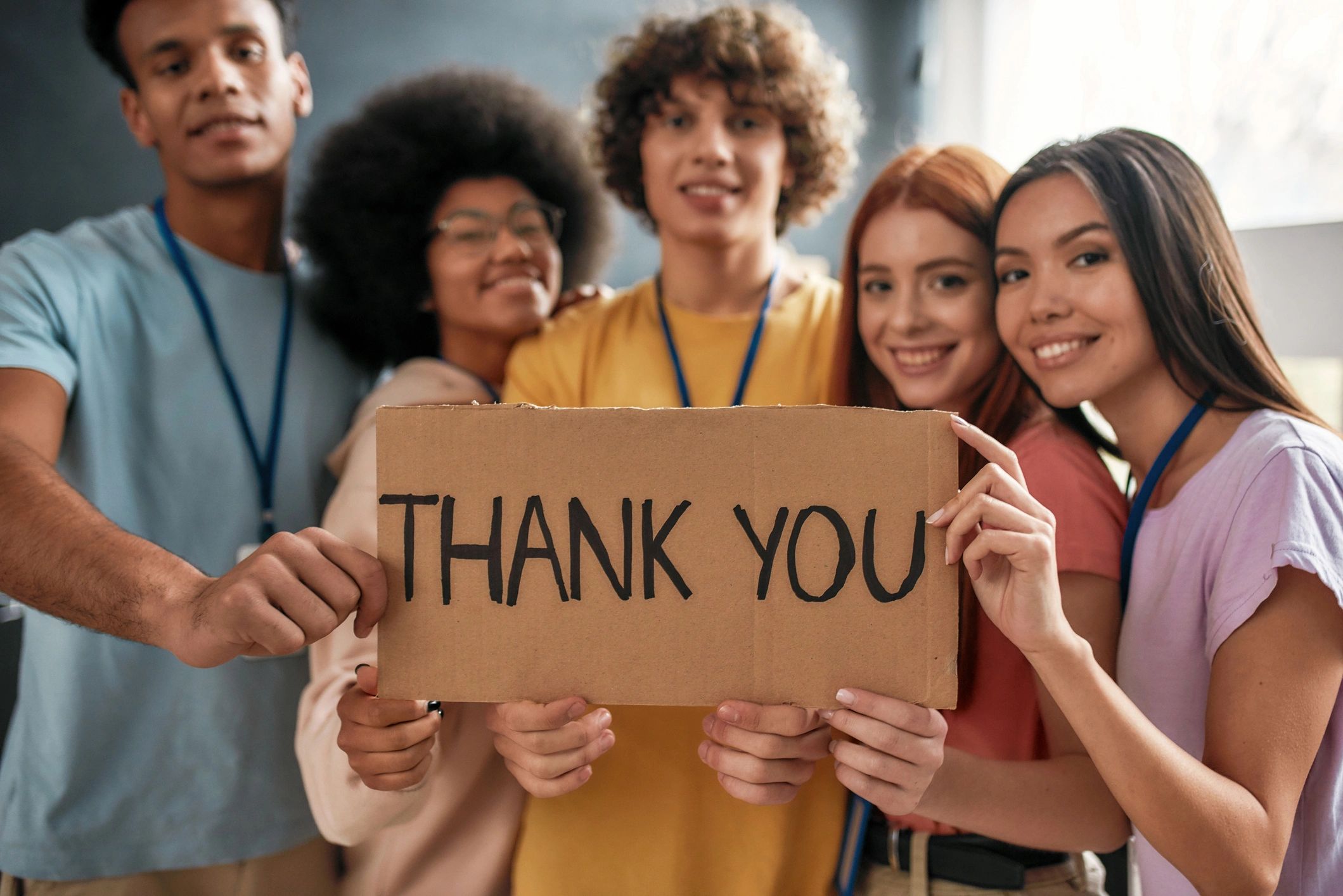 Group of young volunteers holding a thank you sign together.