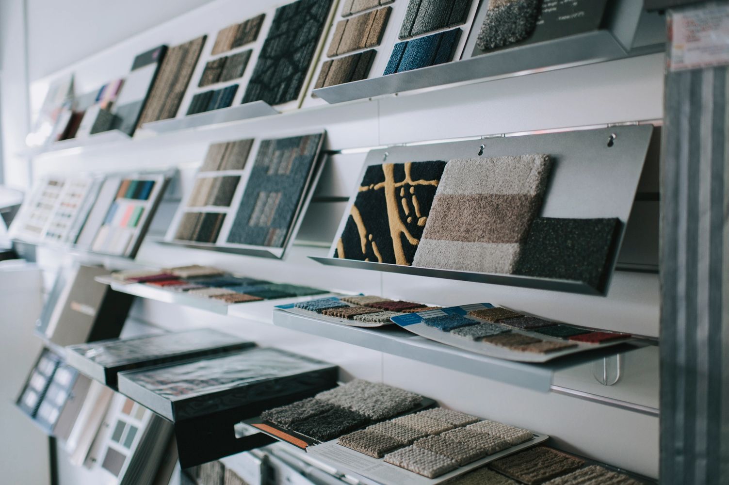 Carpet and fabric samples displayed on angled shelves in a showroom.