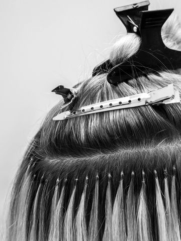 Close-up of hair extensions being attached to natural hair with clips.
