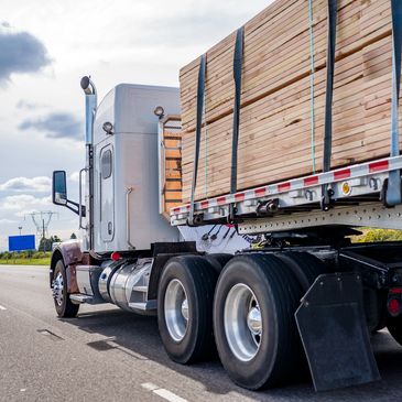 Truck transporting lumber on a highway.