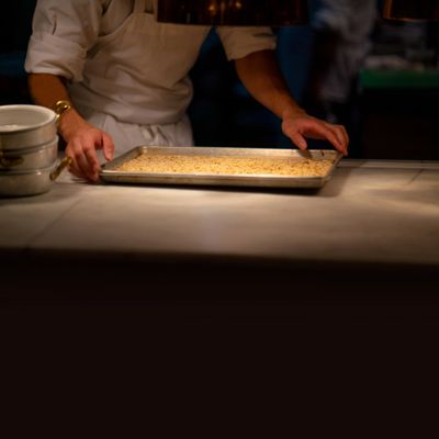 Person preparing a baking tray with dough or crust in a kitchen.