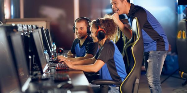 People enjoying gaming on computers with headphones.