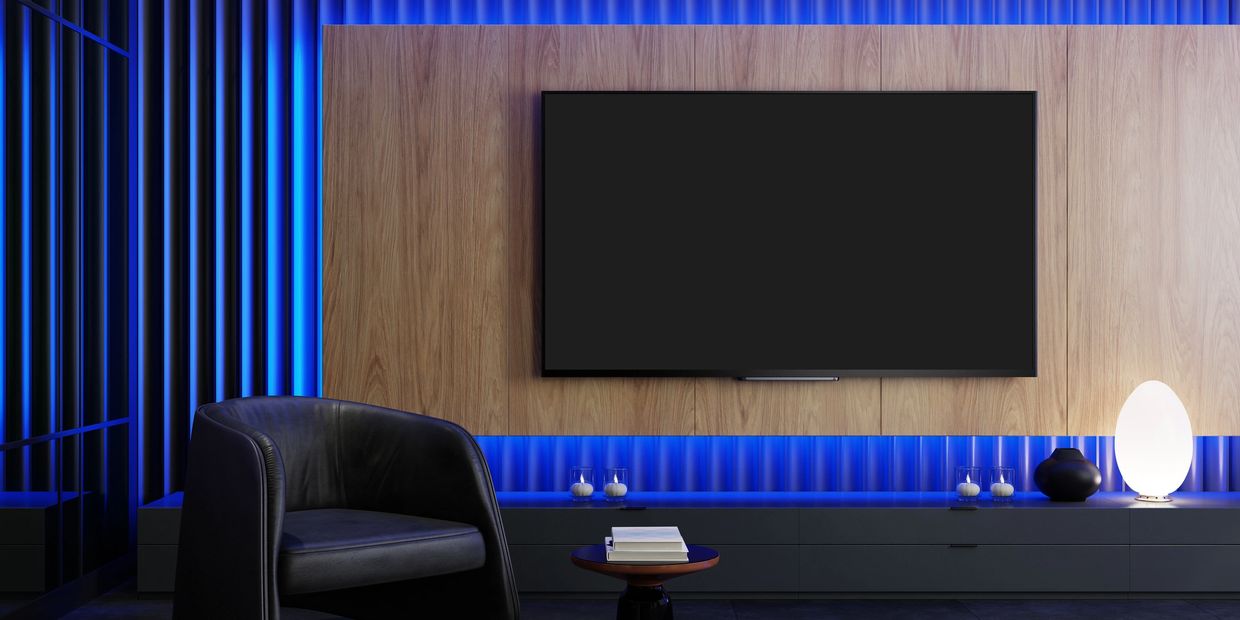 Modern living room with a large TV, leather chair, and blue ambient lighting.