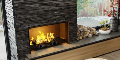 Modern living room with a sleek black fireplace and large window showing autumn trees.