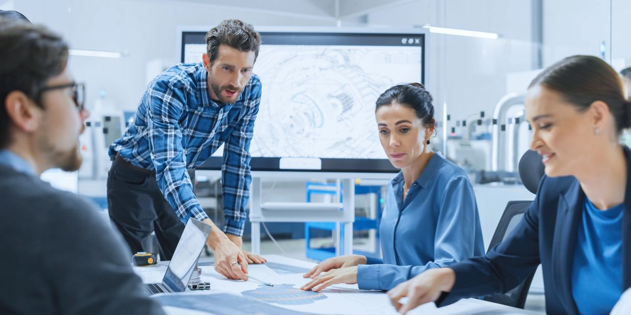 Engineers collaborating on technical blueprints in a modern office setting.