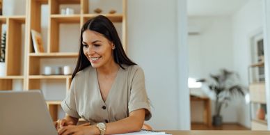 Woman smiling while using laptop at home.