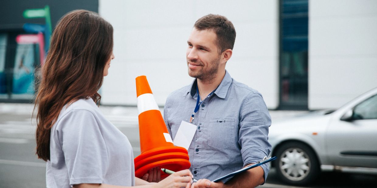 Man and woman talking with traffic cones and clipboard.