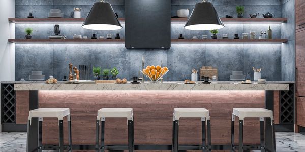 Modern kitchen with marble island and four stools under pendant lights.