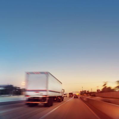 A blurred image of trucks and cars on a highway during sunset.