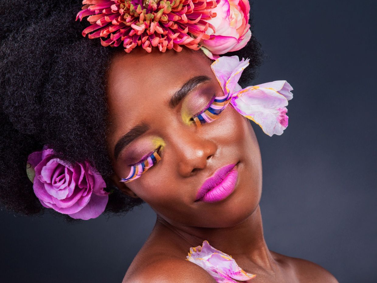 Woman with vibrant makeup and flowers in hair.