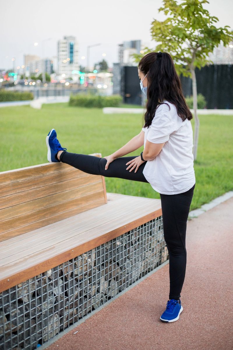 Woman stretching on a bench before running in park