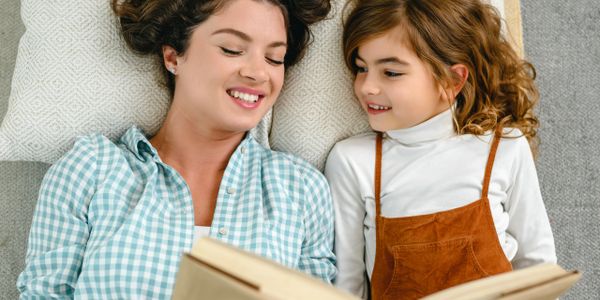Mother and daughter reading a book together on a couch.