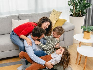 A joyful family playing and laughing together on the living room floor.