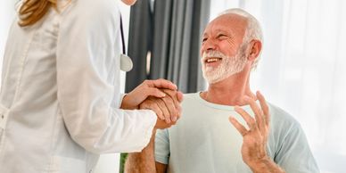 Doctor warmly holding an elderly man's hands during a consultation.