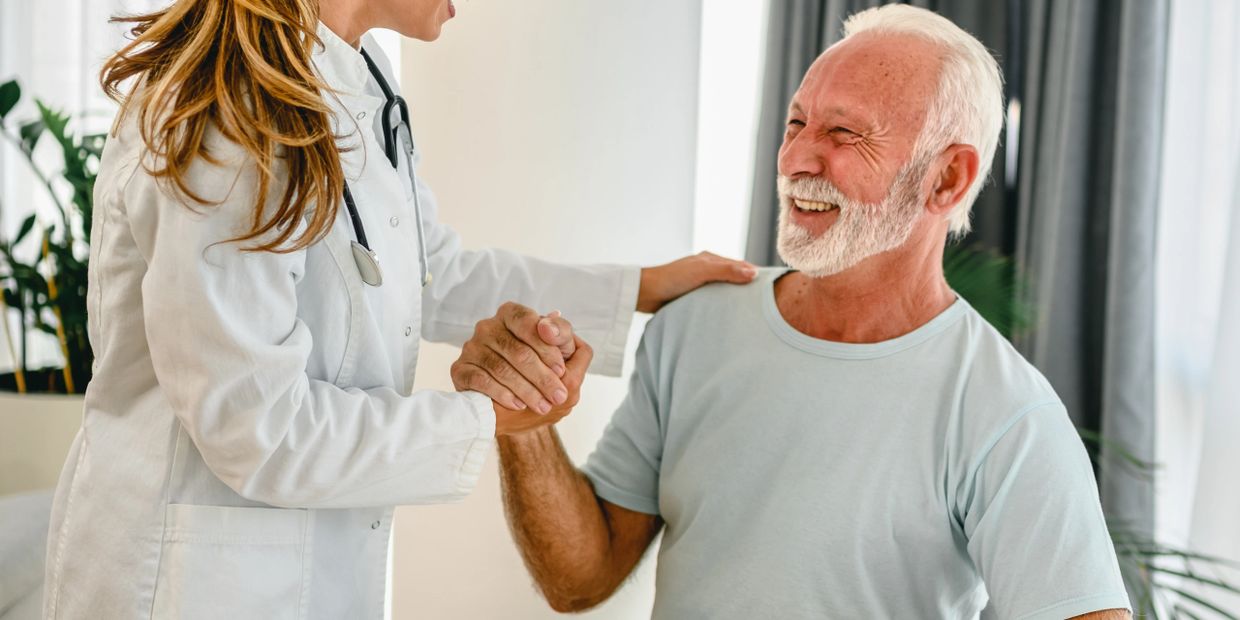 Doctor and elderly man sharing a joyful moment during a consultation.