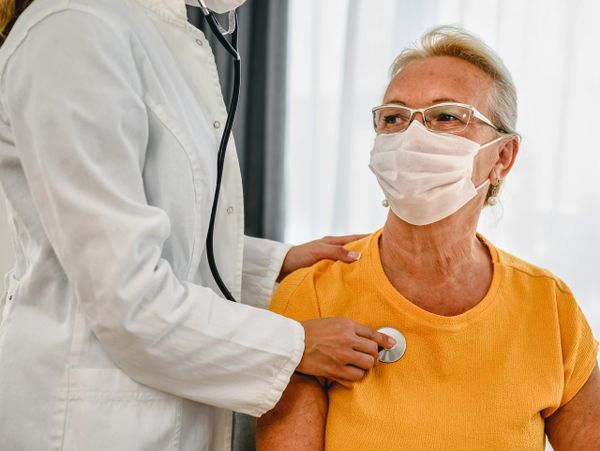 Doctor using stethoscope to check elderly woman's heartbeat.