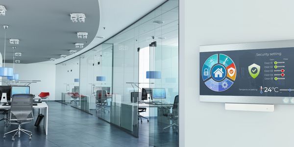 Modern office with glass walls and a digital security and temperature control panel.