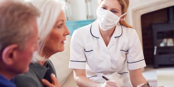 Nurse consulting elderly couple with a mask on.