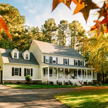 Large white house surrounded by trees in autumn.