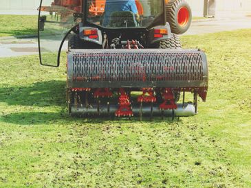 Lawn aerator machine working on a grassy field.