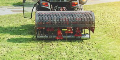 Lawn aerator machine working on a grassy field.