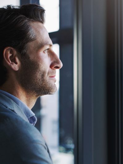 Man in suit looking thoughtfully out of a window.