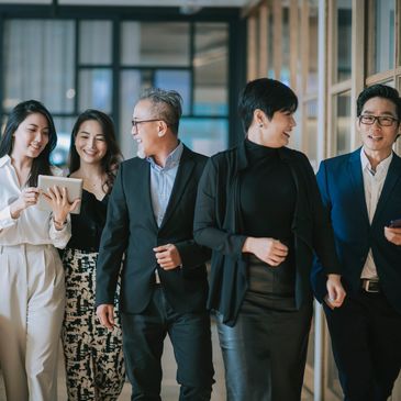 Five professionals walking together, smiling and engaging with devices.