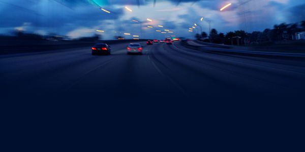 Blurred cars driving on a highway at dusk.