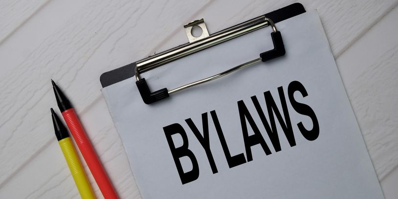 Clipboard with a sign stating bylaws along with a red and yellow mechanical pencil