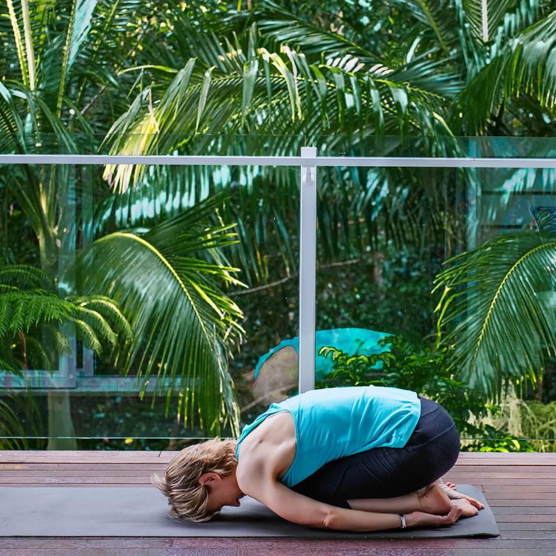 Adult middle aged woman doing yoga on the terrace in a tropical garden