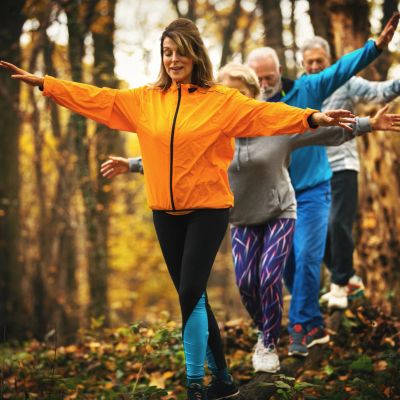 Group practicing balance exercise outdoors in the forest.