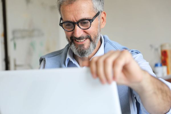 A happy middle-aged professional man opening up laptop.