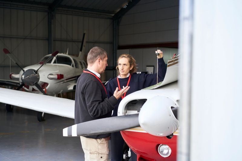 Female flight instructor teaching her student how to do the maintenance of the plane.