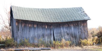 Old, weathered barn with a sagging roof.