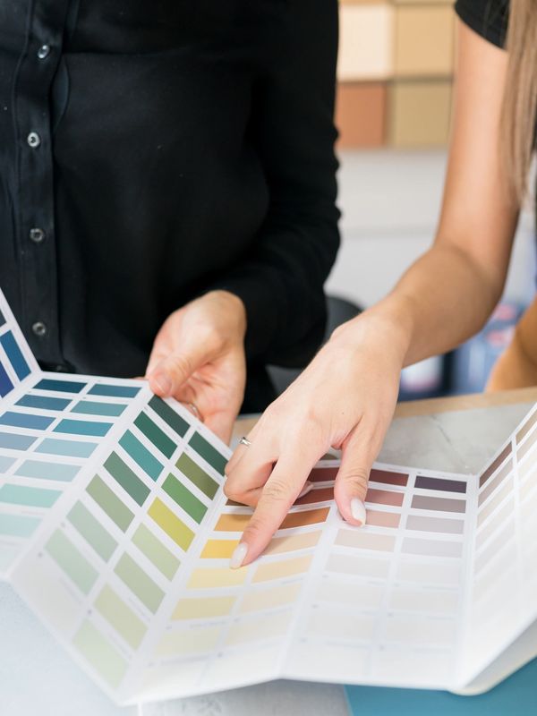 Two people choosing paint colors from a swatch book.