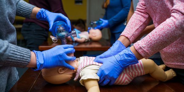 People practicing infant CPR on a doll.