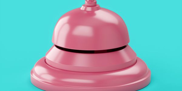 Close-up of a shiny pink service bell on a turquoise background.
