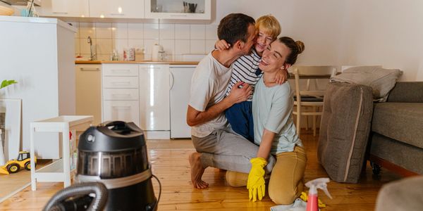 A happy family hugging in their clean kitchen after cleaning together.
