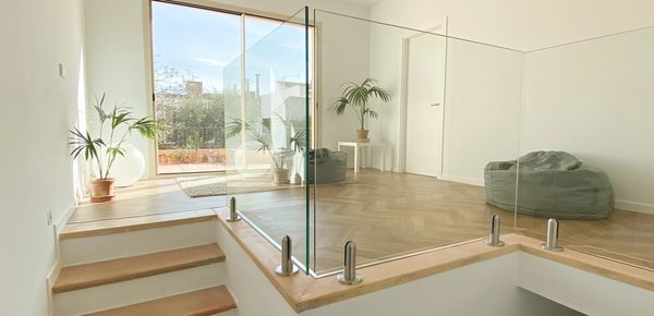 Bright, modern room with glass railing and wooden stairs.