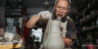 Man sculpting a clay vase.