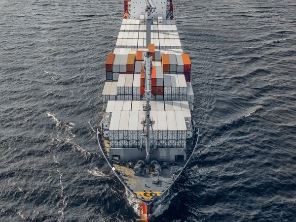 A cargo ship loaded with containers sailing on the ocean.