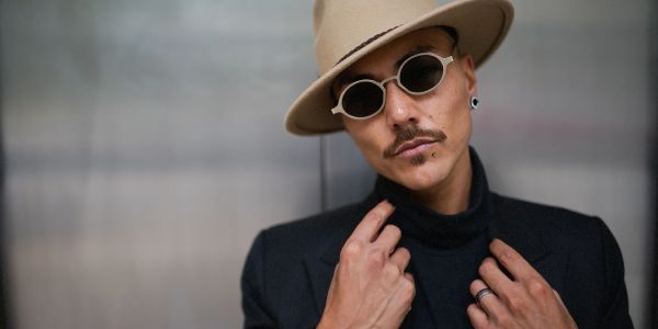Stylish man wearing a beige hat and round sunglasses.